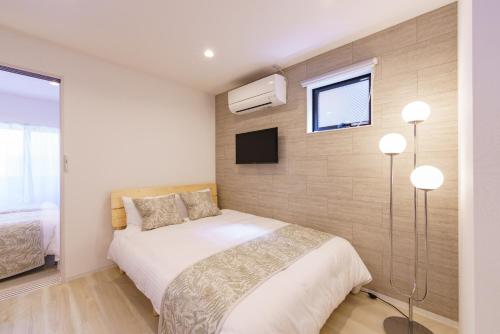 a bedroom with a bed and a tv on a wall at Serene Stay Nagoya JADE 101 in Nagoya