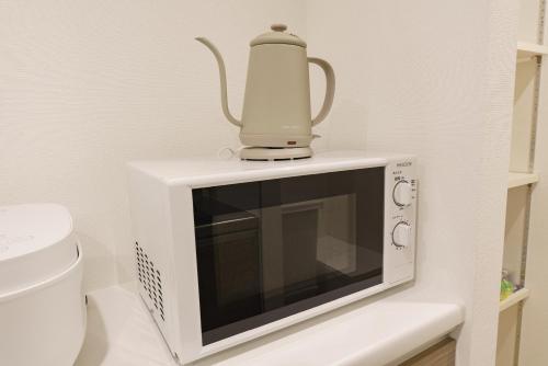 a microwave with a kettle on top of it at Serene Stay Nagoya JADE 101 in Nagoya