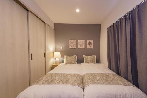 a bedroom with a large bed and curtains at Serene Stay Nagoya JADE 101 in Nagoya
