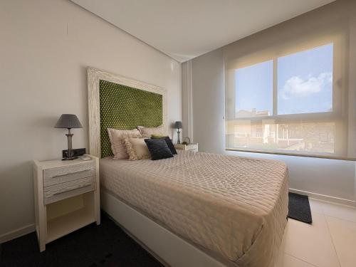 ein weißes Schlafzimmer mit einem Bett und einem Fenster in der Unterkunft Bioko I CABO ROIG - Garden, WiFi, Parking, Pool & Sea View in Orihuela