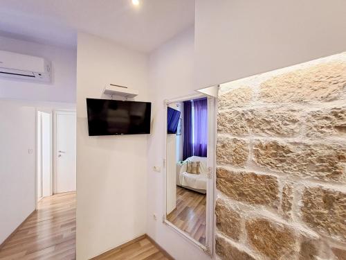 a room with a stone wall with a tv on a wall at Medulić Palace Rooms & Apartments 2 in Šibenik