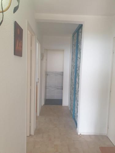 a hallway with white walls and a blue and white door at Bel appartement spacieux front de mer in Le Barcarès