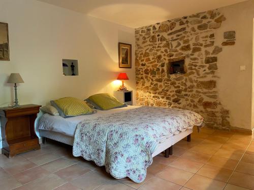 une chambre avec un lit et un mur en pierre dans l'établissement La Bastide Dambrine, à Sanary-sur-Mer