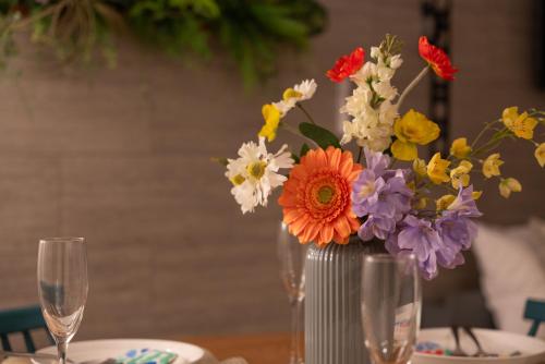 a vase of flowers sitting on a table with glasses at Serene Stay Nagoya JADE 101 in Nagoya