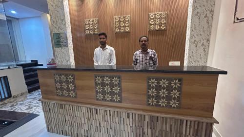 two men standing behind a counter in a room at SANIDHYAM by HOTEL SAHU Near Kashi Vishwanath Temple Gate in Varanasi
