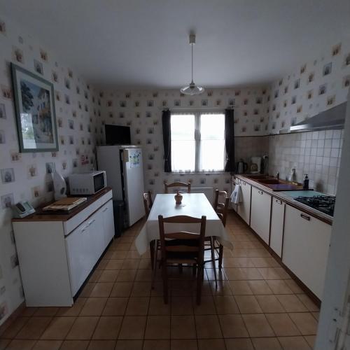 a kitchen with a table and chairs and a refrigerator at La Maison Trèfle in Vieux-Rouen-sur-Bresle