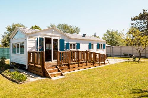 une petite maison avec un porche et une terrasse dans l'établissement Mobile Home - 700m de la plage, à Saint-Georges-de-la-Rivière