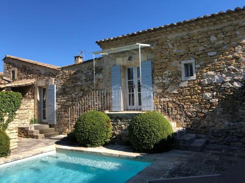 une maison en pierre avec une piscine en face de celle-ci dans l'établissement PETIT MIRACLE, Oppède, à Oppède