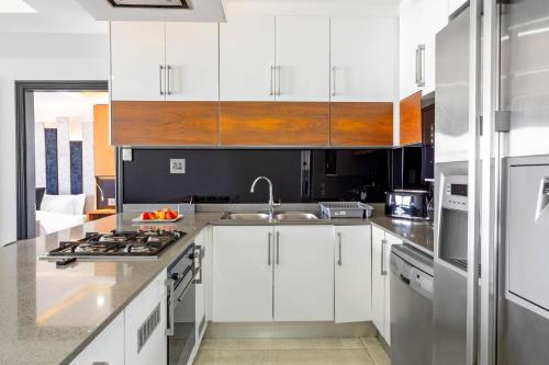 a kitchen with white cabinets and stainless steel appliances at Sairia House by Host Agents in Durban