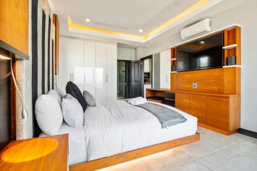 a bedroom with a white bed and a flat screen tv at Sairia House by Host Agents in Durban