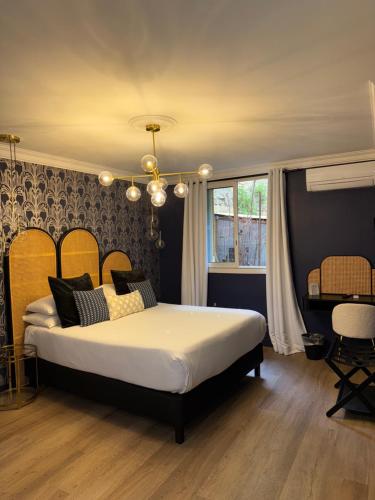 a bedroom with a large bed and a chandelier at La Caravelle in Aix-en-Provence