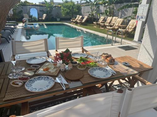 - une table avec des assiettes de nourriture à côté de la piscine dans l'établissement Mavi Yengeç Çeşme Butik Otel, à Çeşme