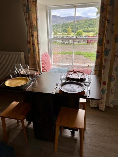 a table with glasses and plates on it with a window at Church Cottage in Helmsdale