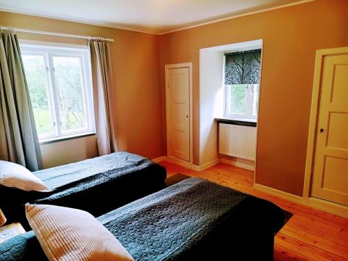 a bedroom with two beds and two windows at Ekebo Guesthouse in Svalöv