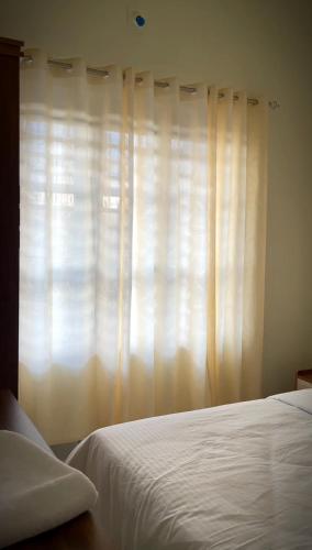 a bedroom with a white bed and a window at MIDDLE WAYANAD HOLYDAY Inn in Kaniyāmbetta
