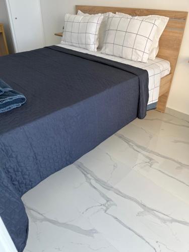 a bed with a blue blanket and white pillows at Ble Property Atlas 8 in Loutraki