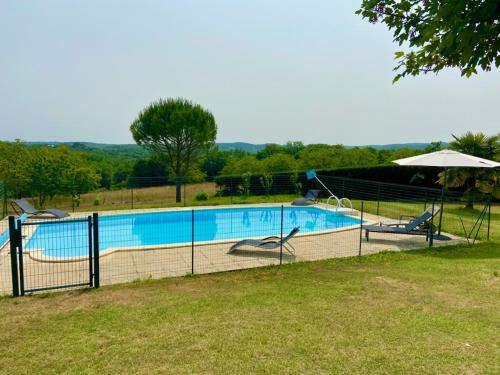 a swimming pool with chairs and an umbrella at Maison de vacances in Nadaillac
