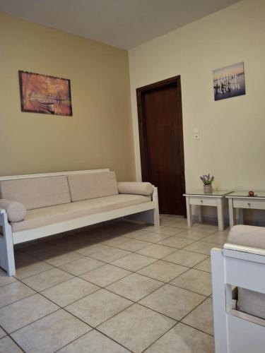 a living room with a white couch and two tables at Lola's Hotel in Plataniás
