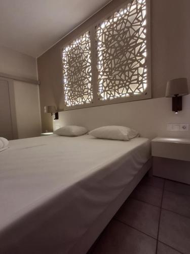 a bed in a room with two windows and a sink at Lola's Hotel in Plataniás