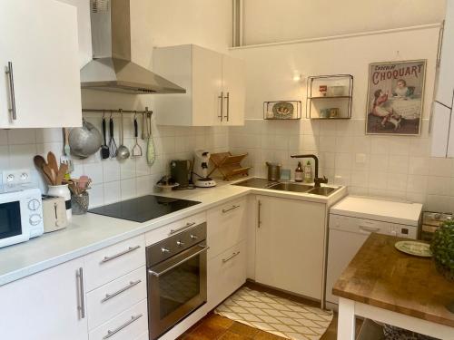 une cuisine blanche avec un évier et un micro-ondes dans l'établissement Le Duplex- La vue des Remparts - Historic Center, à Dinan