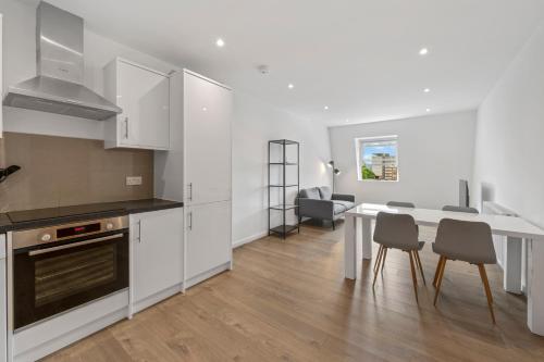 a kitchen with white cabinets and a table and chairs at Prime Location Flats in London