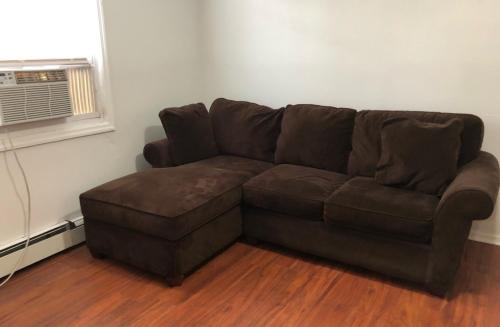 a brown couch in a living room with a window at Large and private apartment in convenient area sleeps up to 5 people comfortably in Elizabeth