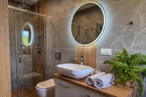 a bathroom with a sink and a toilet and a mirror at Beskidzki Zakątek Ustroń - Przytulny domek z balią i kominkiem, idealny na relaks i ucieczkę od miasta in Ustroń
