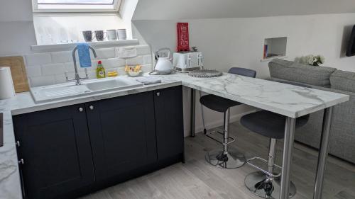 a kitchen with a sink and a counter with stools at The Lodge in Felsted