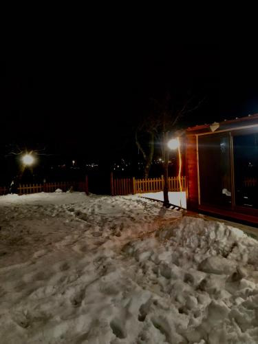 a pile of snow in front of a house with lights at Bujtina Pllumi Theth in Theth