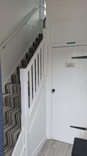 a hallway with a white staircase and a door at The Lodge in Felsted