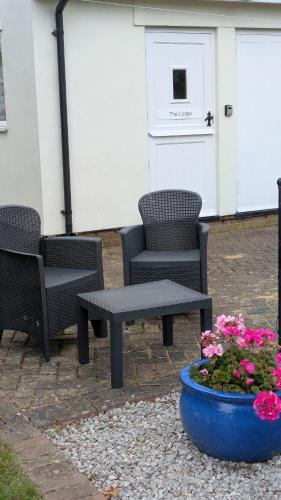 a group of chairs and a table and a pot of flowers at The Lodge in Felsted