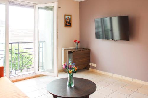 un salon avec un vase de fleurs sur une table dans l'établissement Apartment with balcony near the city center, à Saint-Denis