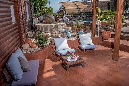 an outdoor patio with two chairs and a table at כחול ירוק בכפר - בקתות מהממות עם ג'קוזי ובריכה מחוממת in Had Nes