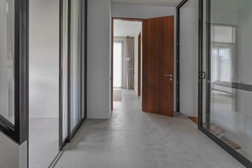 an empty hallway with a wooden door and glass doors at Stark villas - modern villa with roof top in Uluwatu