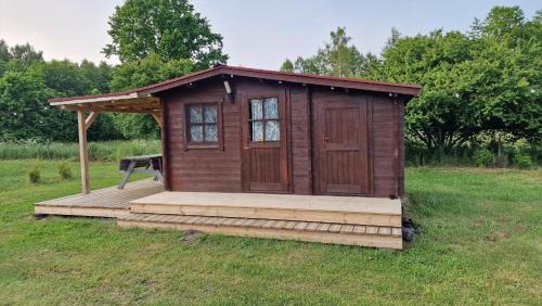 a wooden out house with a deck in a field at SP camping Spāres Prieduļi in Nīca