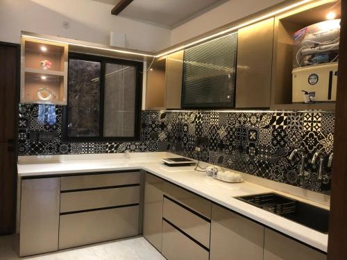 a kitchen with white cabinets and black and white tiles at The Divine Villa ! in Indore