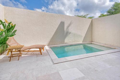 a swimming pool with a bench and a chair next to a wall at Stark villas - modern villa with roof top in Uluwatu