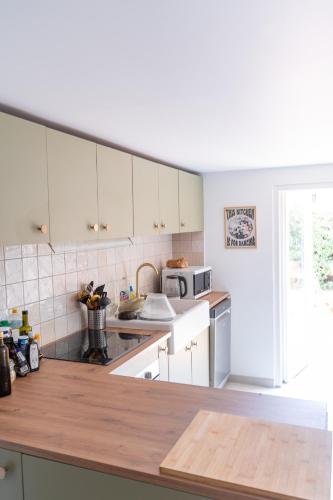 une cuisine avec des armoires blanches et un comptoir en bois dans l'établissement La Maison Léon, à Biscarrosse