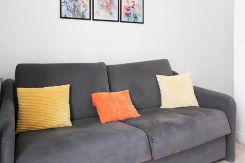 trois oreillers sur un canapé gris dans un salon dans l'établissement Charming and bright in the heart of Paris, à Paris