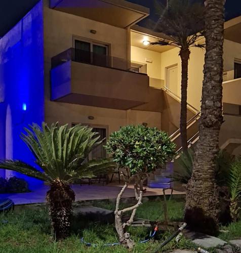 a building with palm trees in front of it at night at Lola's Hotel in Plataniás