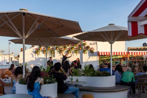 a group of people sitting at a restaurant under umbrellas at The Loft House Sevilla in Seville