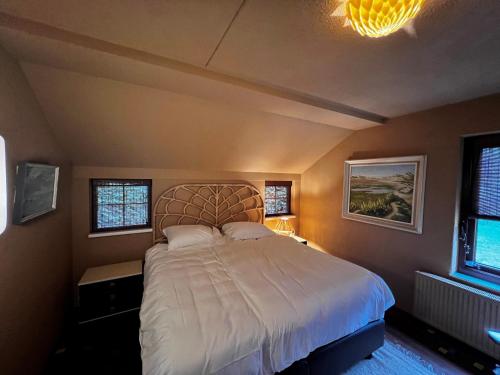 a bedroom with a large bed and two windows at Het Boshoekje Bosweg 6 Burgh-Haamstede in Burgh Haamstede