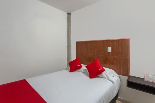 アトリスコにあるCapital O Hotel Emperadores Inn, Atlixcoのベッドルーム(白いベッド、赤い枕付)