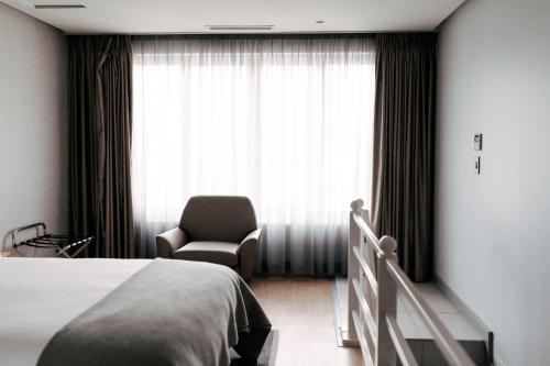 a bedroom with a bed and a chair and a window at Krystal Beach Hotel in Gordonʼs Bay