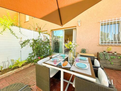 un patio avec une table, des chaises et un parasol dans l'établissement Coquet T2 à Sanary-sur-mer en rez-de-jardin, à Sanary-sur-Mer