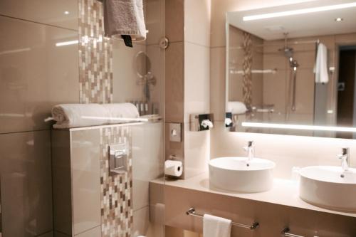 a bathroom with two sinks and a mirror at Krystal Beach Hotel in Gordonʼs Bay