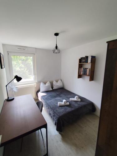 a bedroom with a bed and a table and a window at Flat near Strasbourg in Offendorf