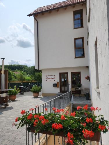 a building with red flowers on a balcony at Landgasthof Hummel in Ebensfeld