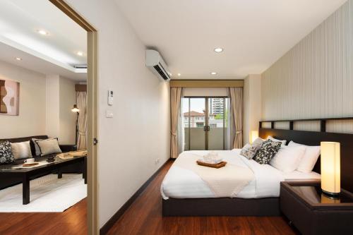 ein Schlafzimmer mit Bett, Schreibtisch und Sofa in der Unterkunft King-Suite with Balcony and a full Kitchen near ThonglorBTS in Klong Toi