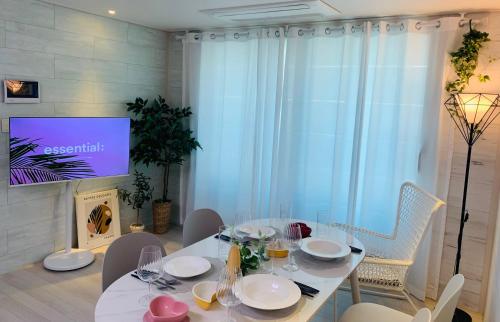 a dining room with a white table and a tv at Cozy Erin Stay, Seoul in Seoul